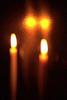 Two candles and their reflections surrounded by darkness
