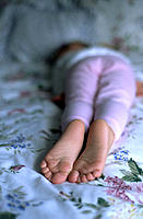 Young girl sleeping on bed with feet hanging over