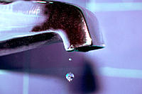 A single water drop falling from the faucet