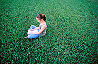 9 year old girl sitting on grass, drawing in notebook