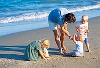 Mother with children collecting sea shells at the beach