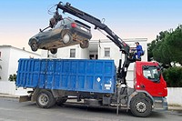 Truck with crane taking car to scrapyard
