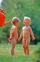 Two year old children take a shower under a watering can. Västerbotten, Sweden