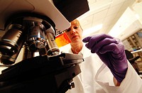 Woman at microscope in hospital or bio lab