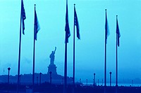 Statue of Liberty and the american flags with a bluish sky