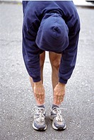 Male jogger stretching by touching his toes.