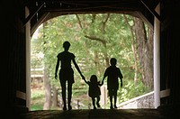 Silhouette of mom with two children in covered bridge. Pennsylvania, USA