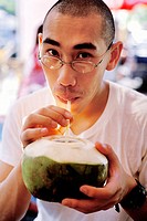 Man drinking coconut milk. Jatujak market. Bangkok, Thailand.