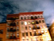 A New York apartment building is captured at night with a blury, pastel effect.