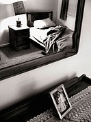 A bedroom s captured in black and white from the perspective of shooting into a mirror.