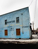 A blue, brick warehouse is captured in a city in the Northeastern United States during winter.
