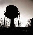 The sillouette of a water tower is captured in black and white against a dramatic sky.