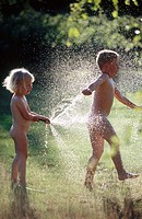 Two children, 3 and 6 years old, playing with water, in direct light. Medle. Vasterbotten. Sweden.