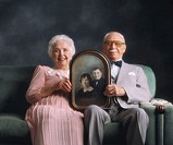 Elderly couple holding photo from when they were just married.