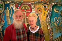 Artist Alan Davey and his wife standing in front of one of his paintings