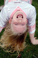 A little girl smiles while upside-down