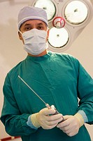 Plastic surgeon with liposuction apparatus in surgery room.