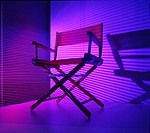 Director´s chair; low-key lighting with blue and magenta light; venetian blind background