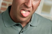 Caucasion man with bandage on tongue; face partially visible. Soft green casual shirt.