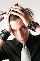 Portrait of teen boy wearing wristbands and a silver tie, pulling his back.