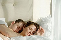 Young couple sleeping and cuddling in bed together