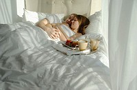 Young couple in bed cuddling with tray of breakfast foods