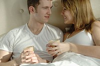 Young couple in bed having coffee together