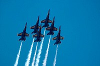 U.S. Navy´s Blue Angels flight demonstration team flying F/A_18 Hornet jets in delta formation with smoke on.