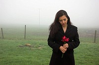 Young woman standing with roses on a cold misty winter morning.