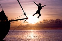 Girl jumping from yacht in sundown. Bora Bora. French Polynesia.