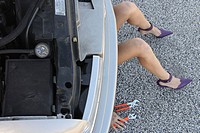 Woman in purple high heels getting under a car fixing it only show her legs, hands and tools.