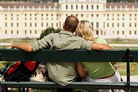 Young Couple Sitting on Bench Looking at Schonbrunn Palace, Vienna, Austria, Europe