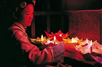 NAXI WOMAN LIGHTING CANDLE LANTERNS MEANT TO BE FLOATED DOWN THE CANALS, LIJIANG, CHINA