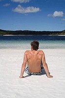 Man sitting on beach, seen from behind. Fraser Island, Australia
