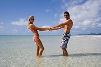 Couple holding hands in the sea. Whitehaven beach, Australia.