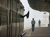 Train conductor waves flag as a signal as he leaves station in Bangalore, India