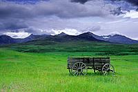Old wagon and Rocky Mountains near Twin Butte, Alberta Canada