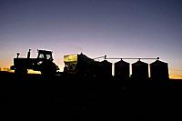 Fall corn harvest in Hardin County Iowa with silhouetted tractor and wagon unloading at state of the art computer aided grain drying bins near Buckeye...