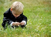 A little boy squatting in the grass