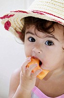 Little girl eating fruit.