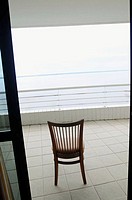 Empty chair in open doorway overlooking ocean