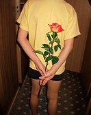 young boy holding rose behind back