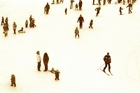 skiers and sledding children on big snowy hill