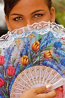 A portrait of a young girl posing with a colorful fan.