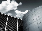 Architectural detail of the building where i straight curves converge on a background of sky with clouds. Photographs in black and white turned blue w...