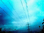 Vista de un poste de suministro de electricidad a través del parabrisas de un coche, en un gris y lluvioso día.