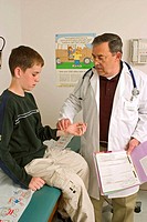 Male doctor, checking the pulse of a teen age boy, during a medical exam in doctor´s office