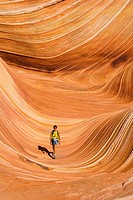 woman walking through a rock formation known as ´The Wave´, North Coyote Buttes,Vermillion Cliffs, Paria Wilderness, Utah, USA.