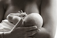 A topless mother tenderly strokes her newborn baby´s head as she breastfeeds him.