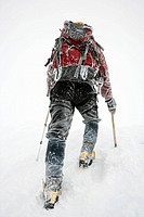 Mountaineer climbing snow covered mountain in whiteout